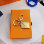 Gold-tone envelope charm and round keyring on an orange box