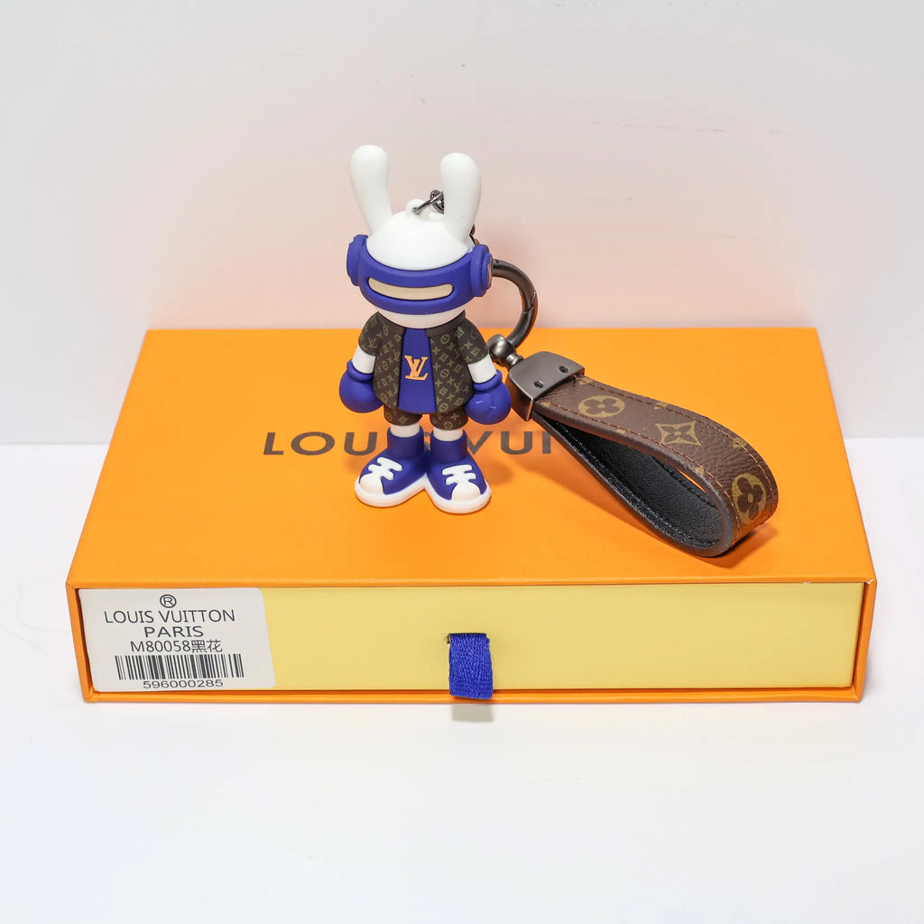 Blue rabbit keychain standing beside a brown monogram loop