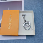 Key-shaped silver-tone keychain resting inside an orange box