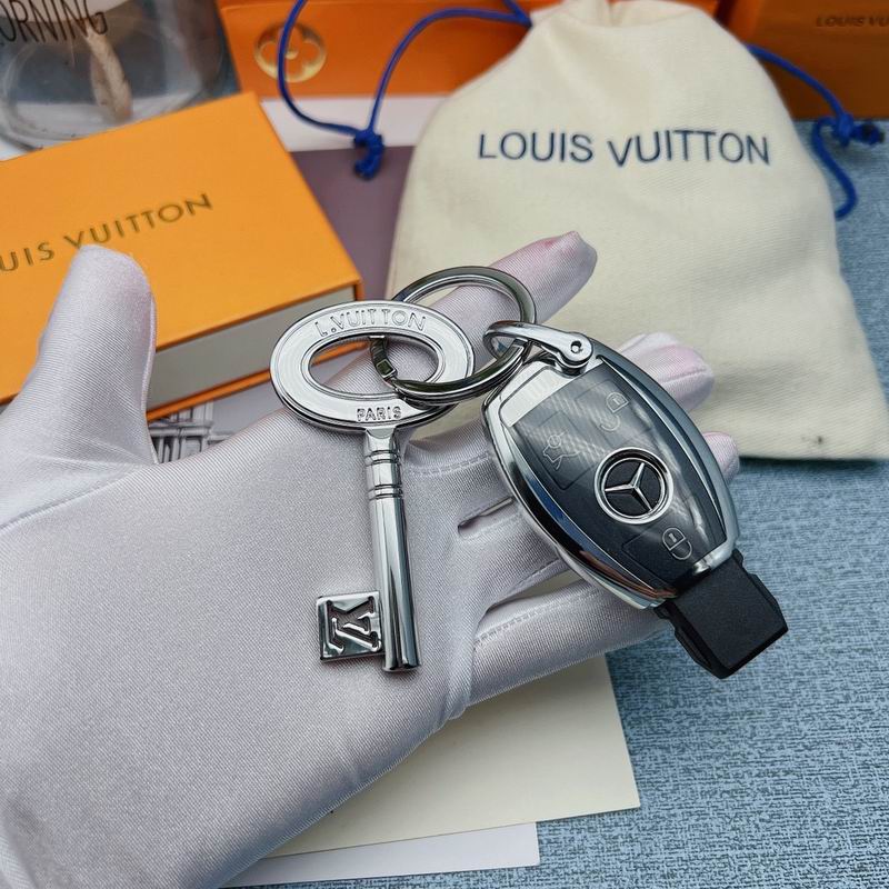 Silver-tone key charm and black car key held in a glove