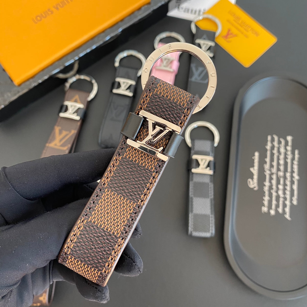 Brown checkered loop key holder held in a dark glove