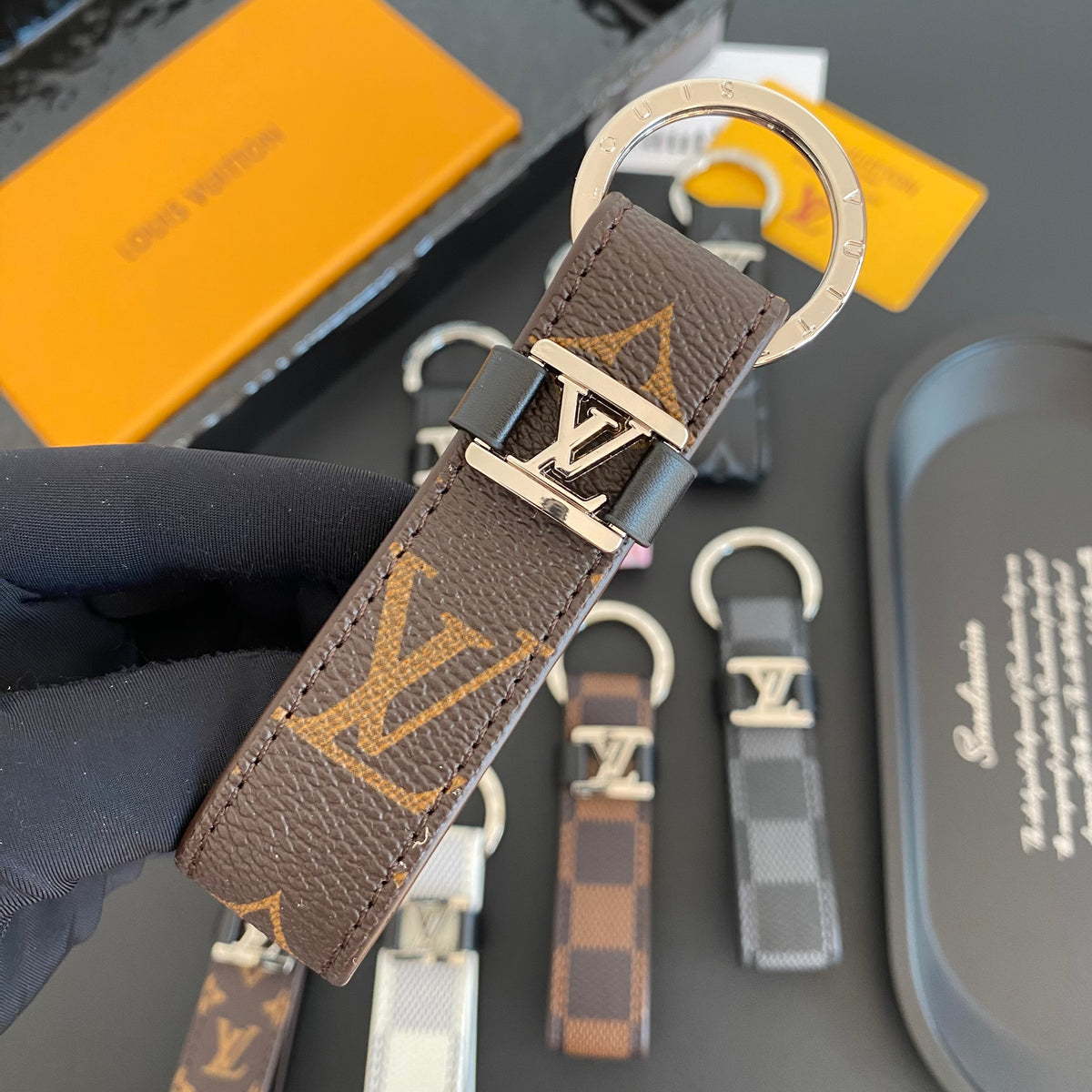 Brown loop key holder with oversized gold-colored monogram lettering