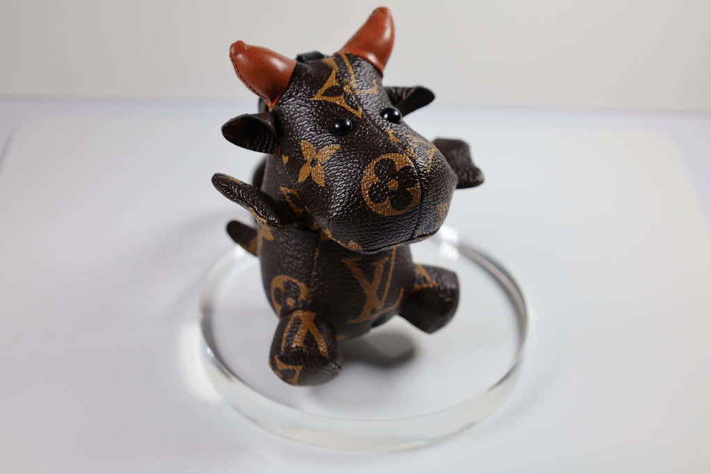 Angled view of brown cow keychain on a clear display