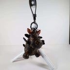 Cow keychain hanging from its wrist strap above a white stand