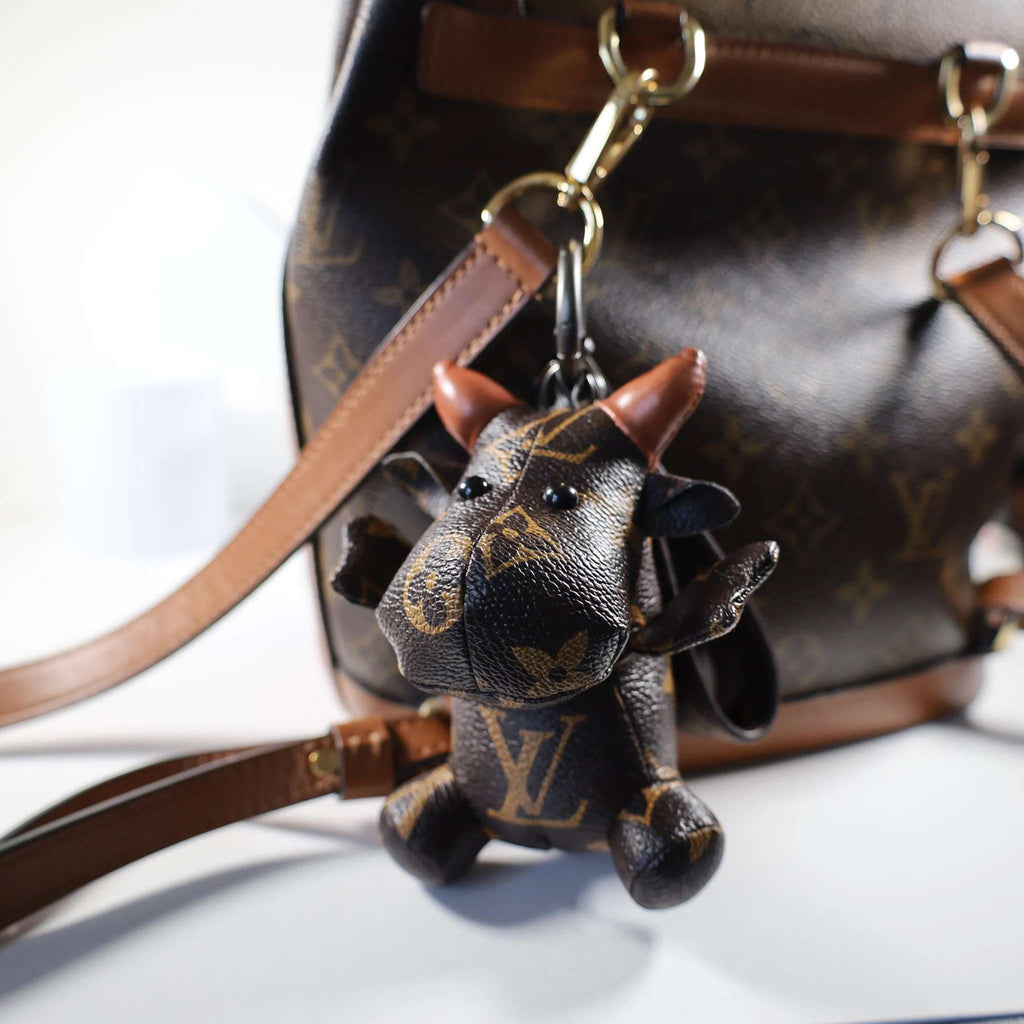 Monogram cow charm hanging from a brown bag