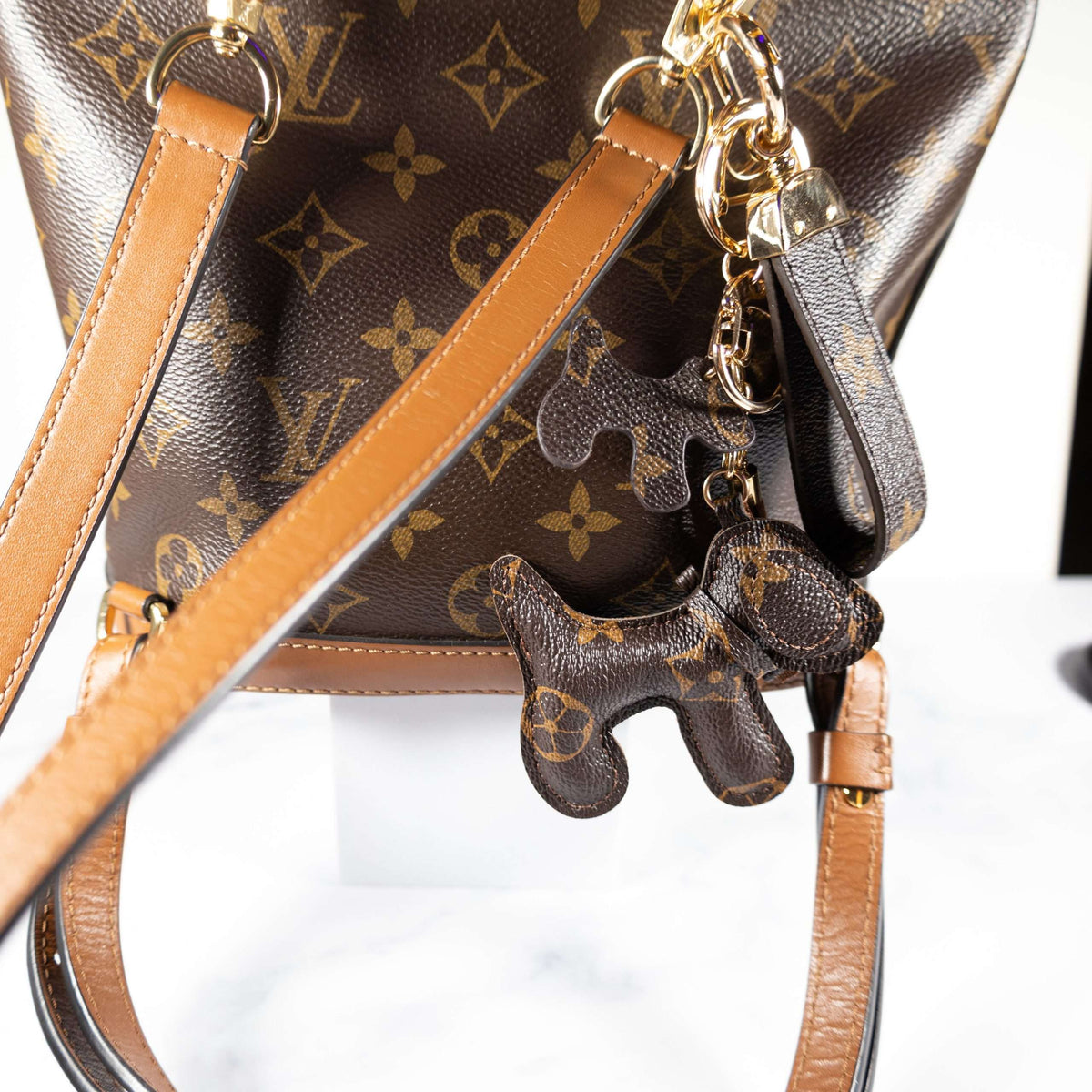 Monogram dog keychain and wrist strap attached to a brown bag