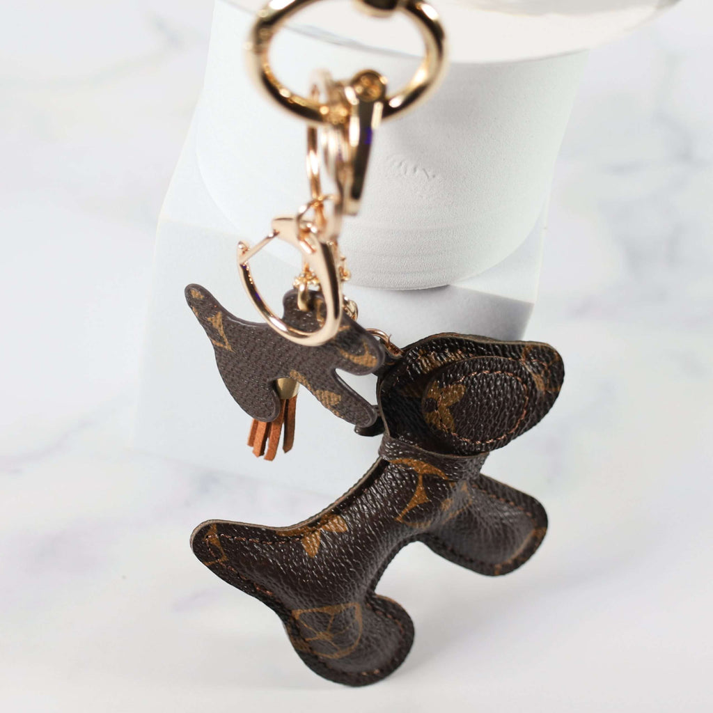 Dog keychain hanging from gold-tone rings beside a white display