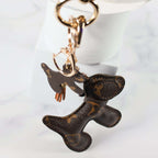 Dog keychain hanging from gold-tone rings beside a white display