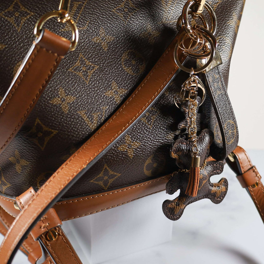 Rear angle of bear charm hanging against a brown bag