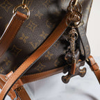 Rear angle of bear charm hanging against a brown bag