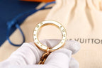 Engraved gold-tone keyring held above a fabric pouch