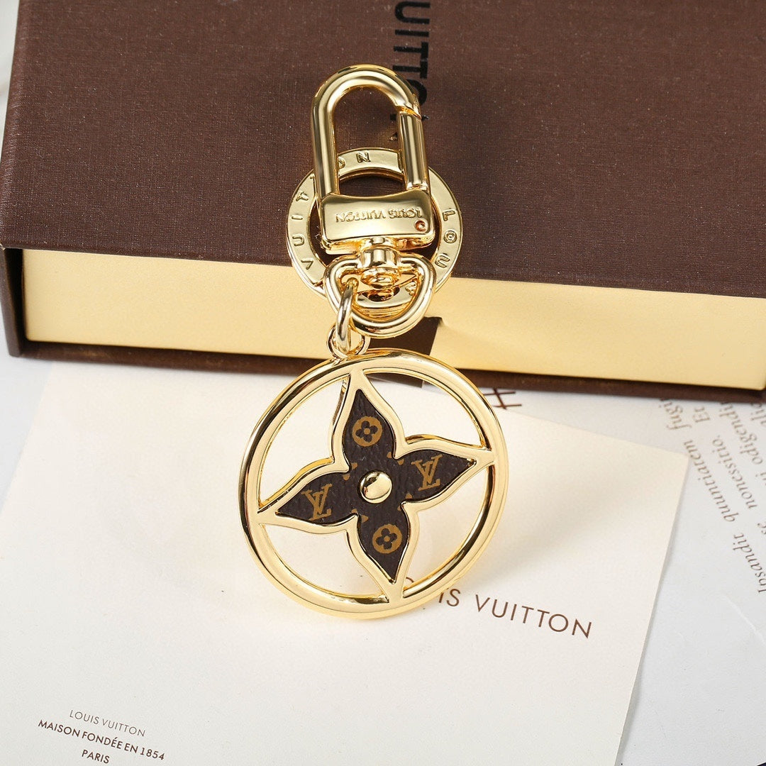 Gold-tone flower keychain displayed upright against a box