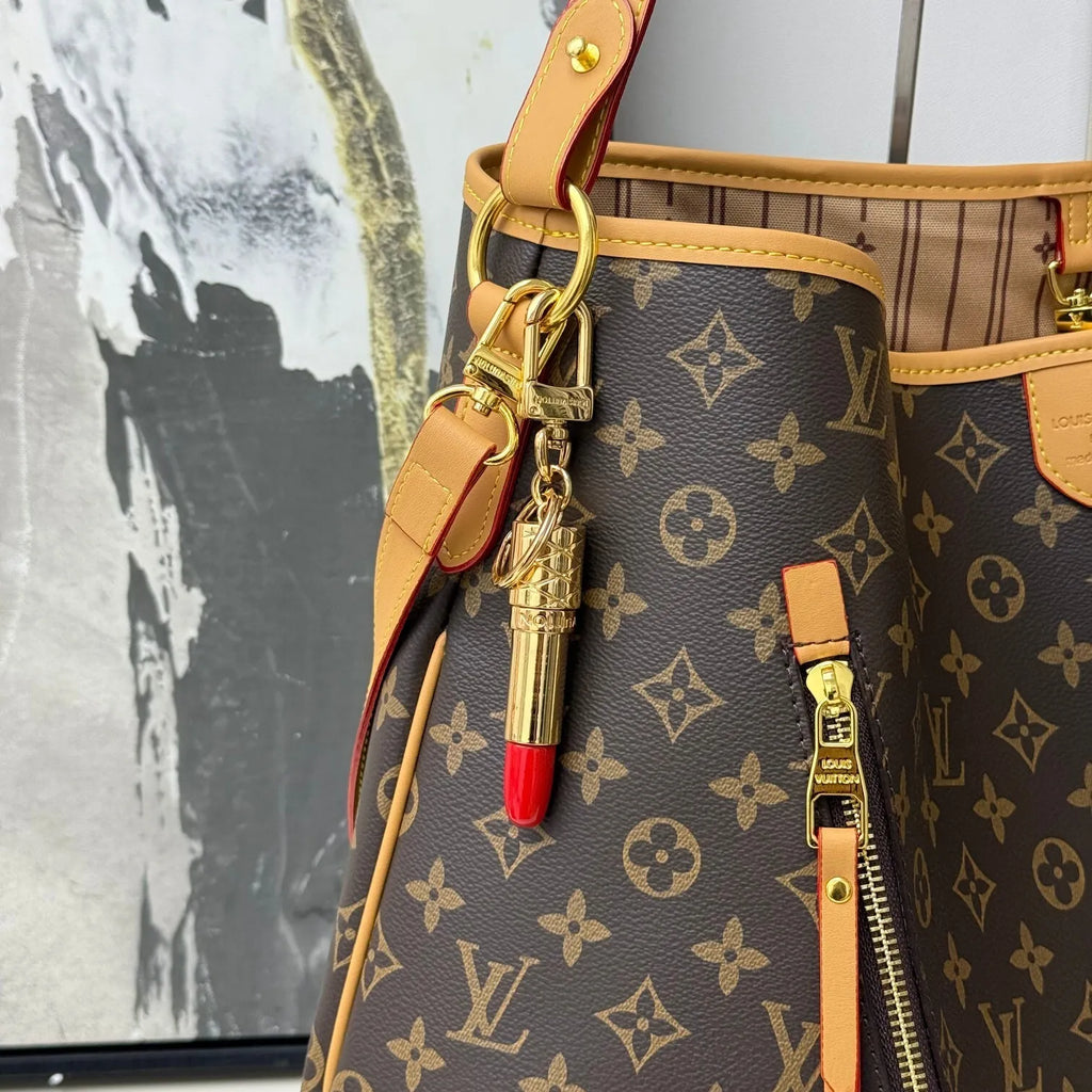 Gold-tone lipstick charm attached to a brown monogram bag