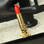 Close-up of red lipstick-shaped pendant with gold-tone patterned barrel