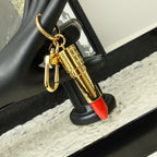 Gold-tone lipstick keychain hanging from a black display stand