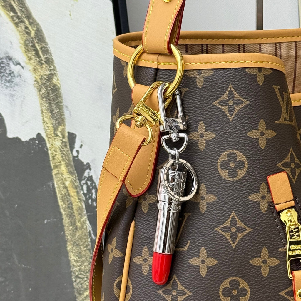 Silver-tone lipstick charm attached to a brown monogram bag