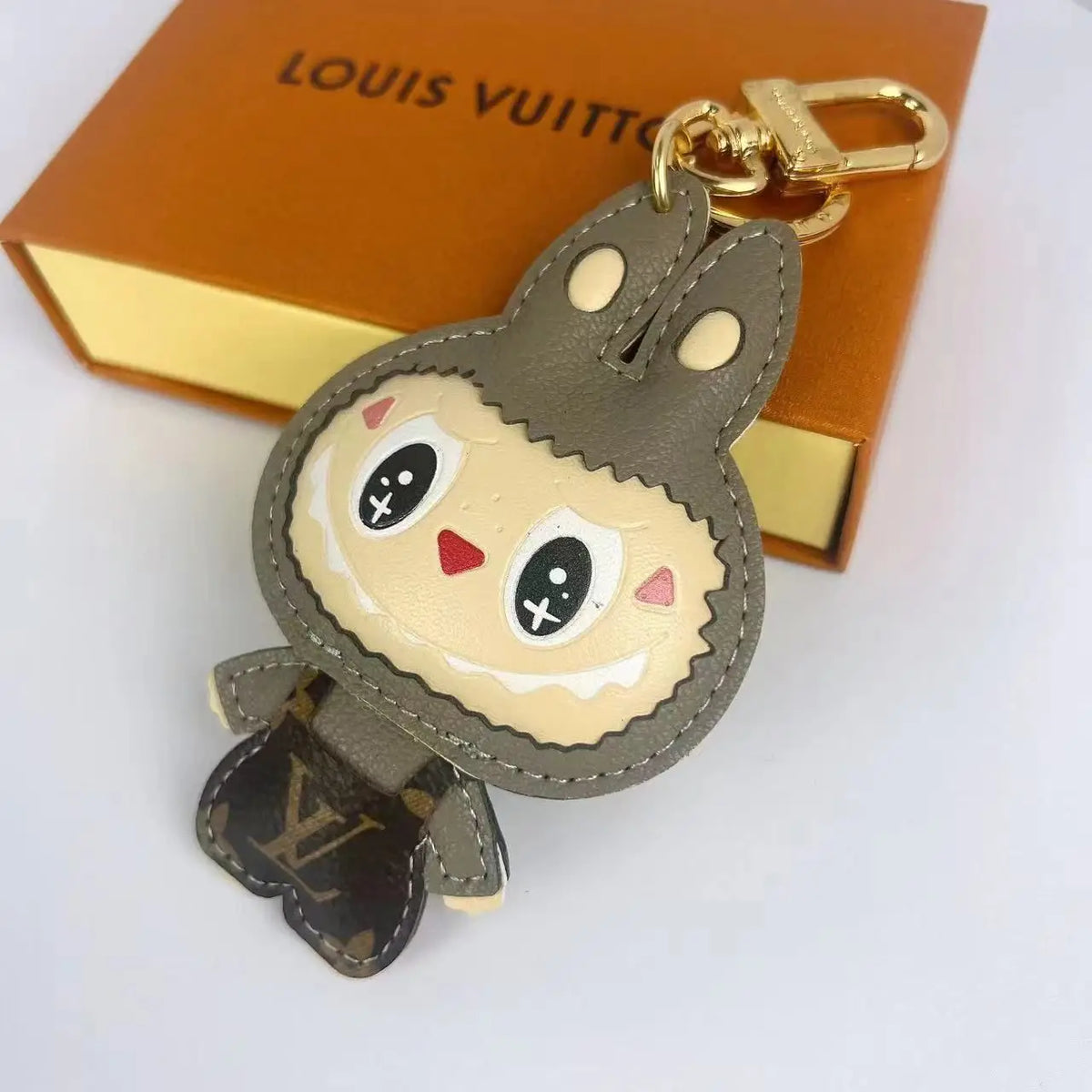 Khaki Labubu keychain with smiling face and gold-tone clasp