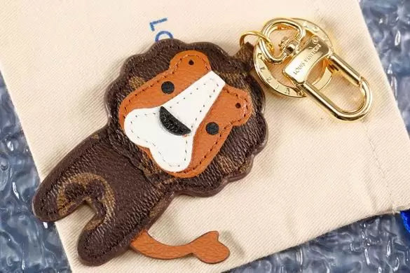 Lion charm with tan mane lying on a cream pouch
