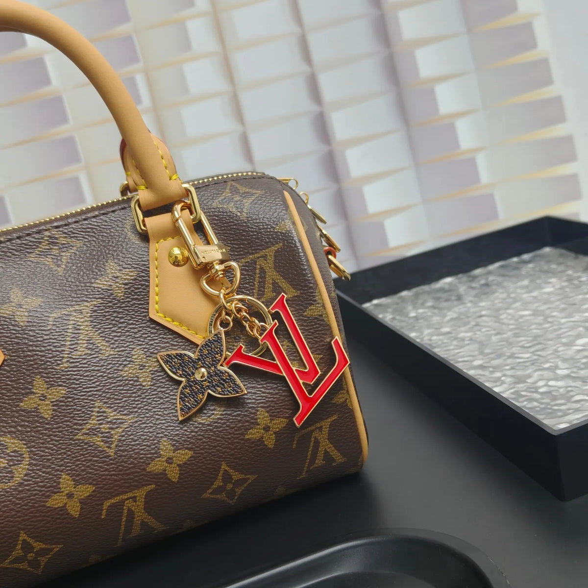 Red LV and flower keychain attached to a monogram bag