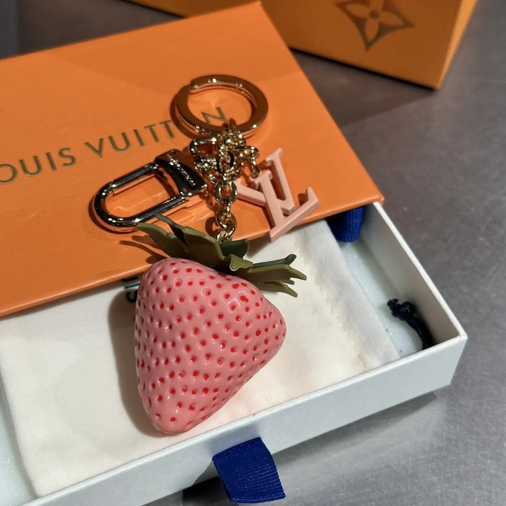 Pink strawberry keychain with green leaves in an open box
