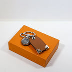 Plain brown reverse of tag keychain beside silver-tone clasp