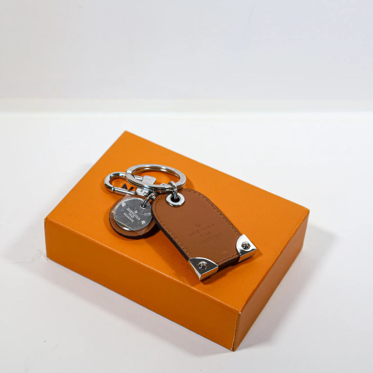 Plain brown reverse of tag keychain beside silver-tone clasp