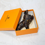 Brown monogram bulldog keychain resting inside an orange box