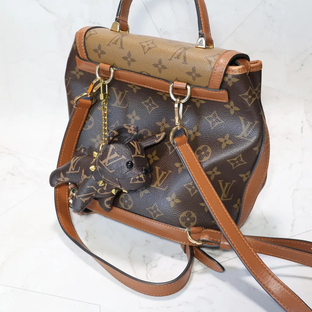 Brown monogram bulldog charm hanging from a matching backpack