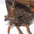 Brown dog charm hanging sideways against a monogram backpack