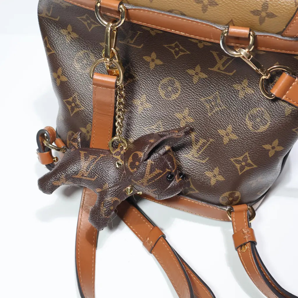 Close view of dog charm and gold-tone chain on backpack