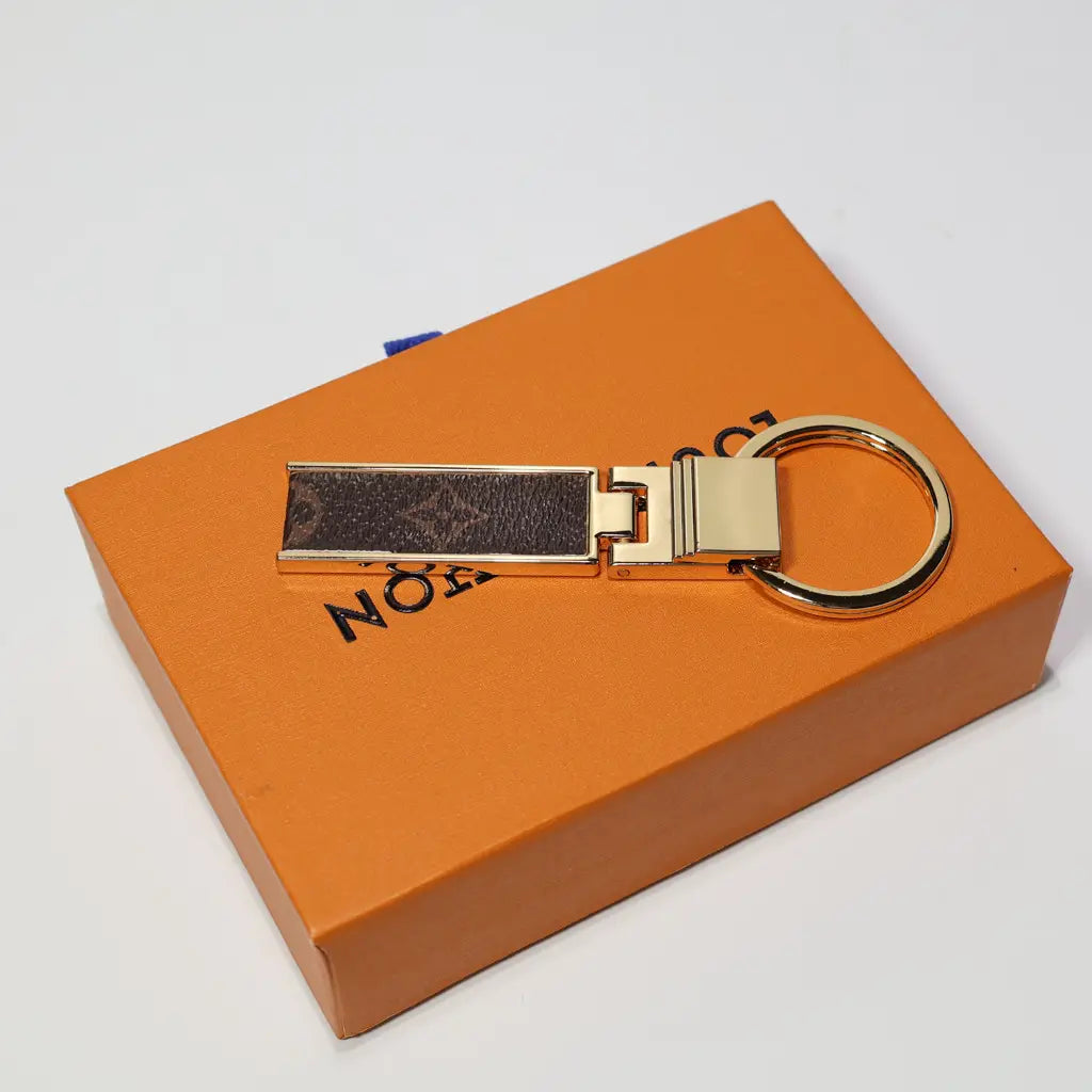 Folding monogram keychain laid flat across an orange box