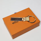 Folding monogram keychain laid flat across an orange box