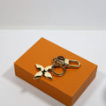 Gold-tone flower keychain with dark center on an orange box