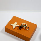 Gold-tone floral keychain laid flat showing dark round pendant