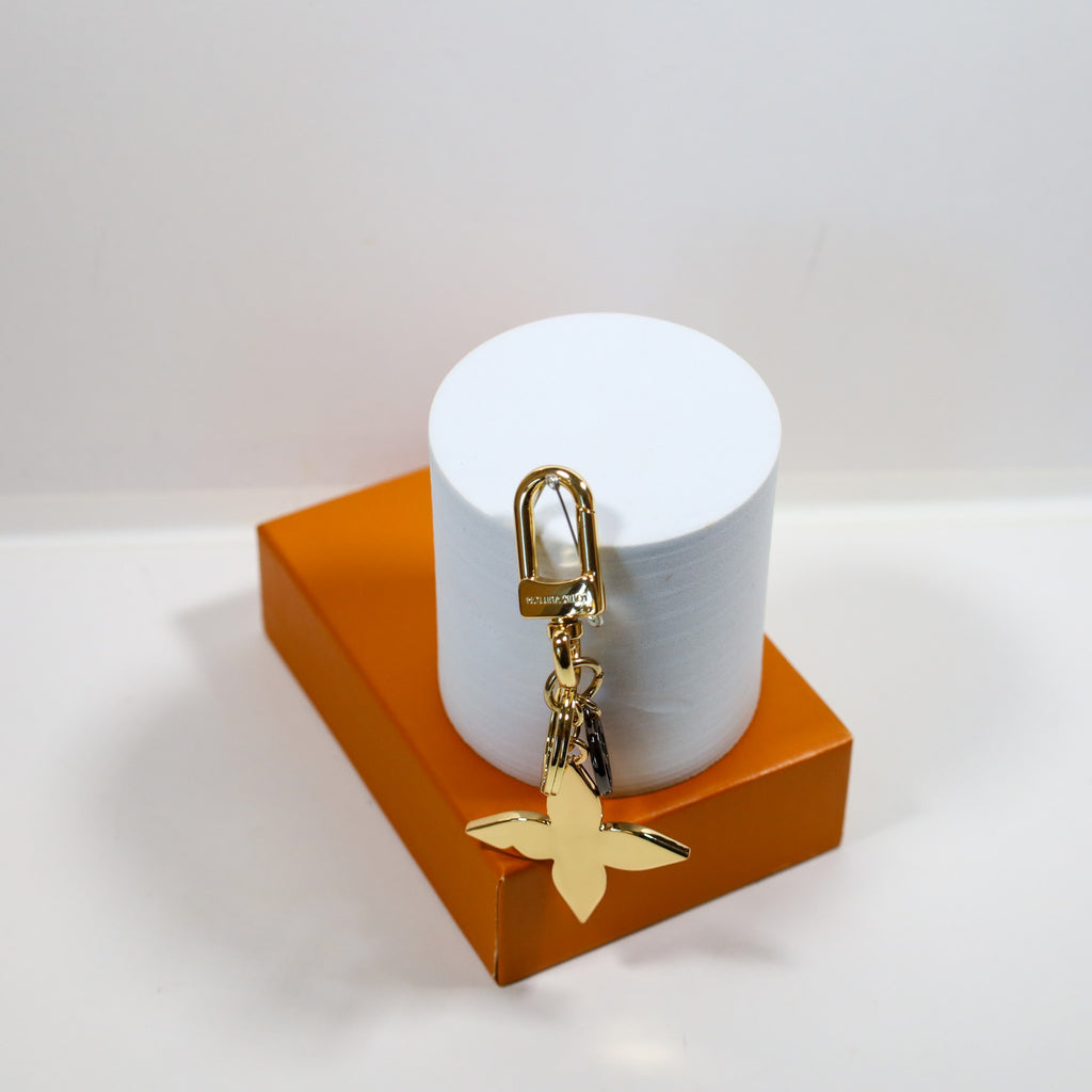 Reverse of gold-tone flower keychain on a white display