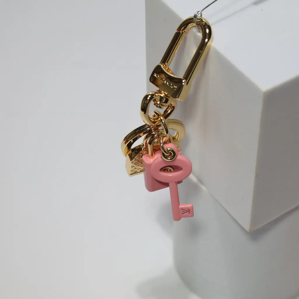 Gold-tone keychain hanging with pink key and lock charms