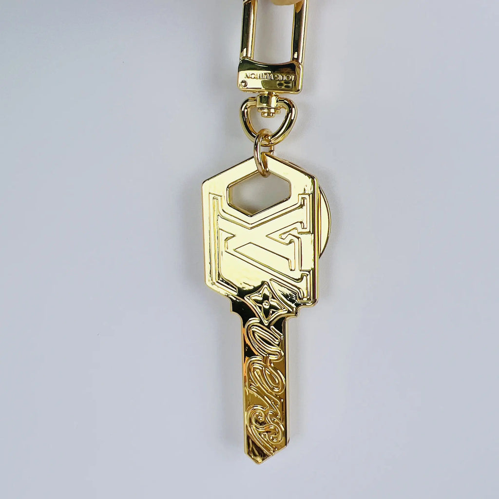Gold-tone LV key pendant hanging vertically from its clasp