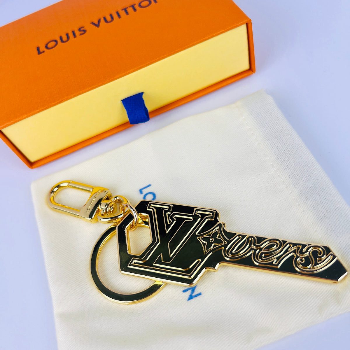 Black and gold-tone LV key charm shown with round ring
