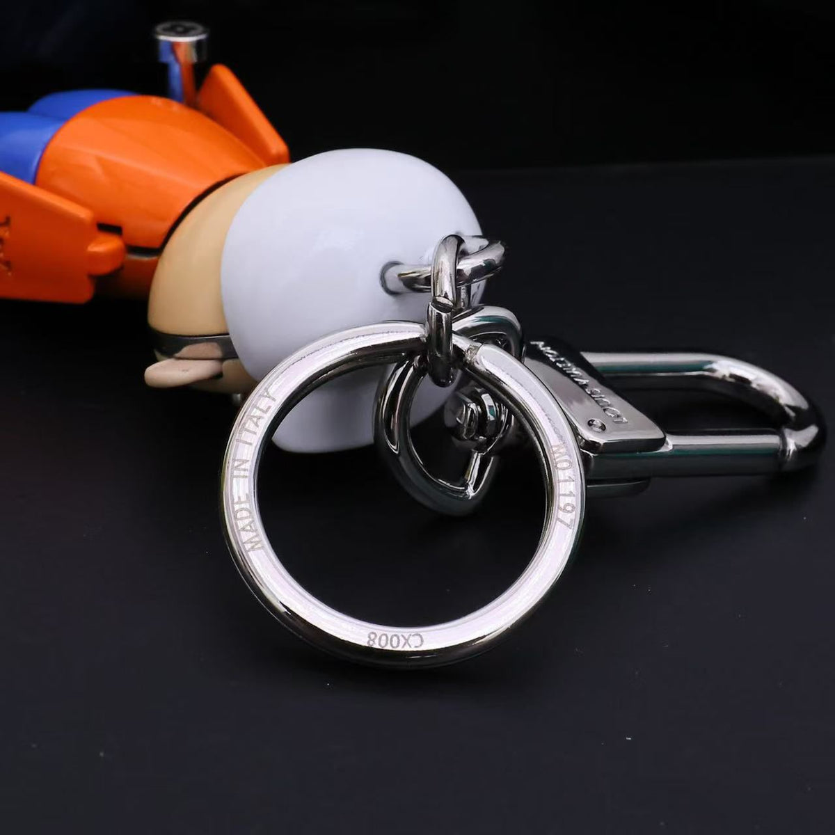 Silver-tone keyring and clasp attached behind the character's white cap