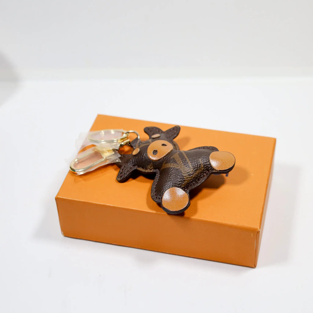 Cow keyring reclining on an orange box with gold-tone hardware