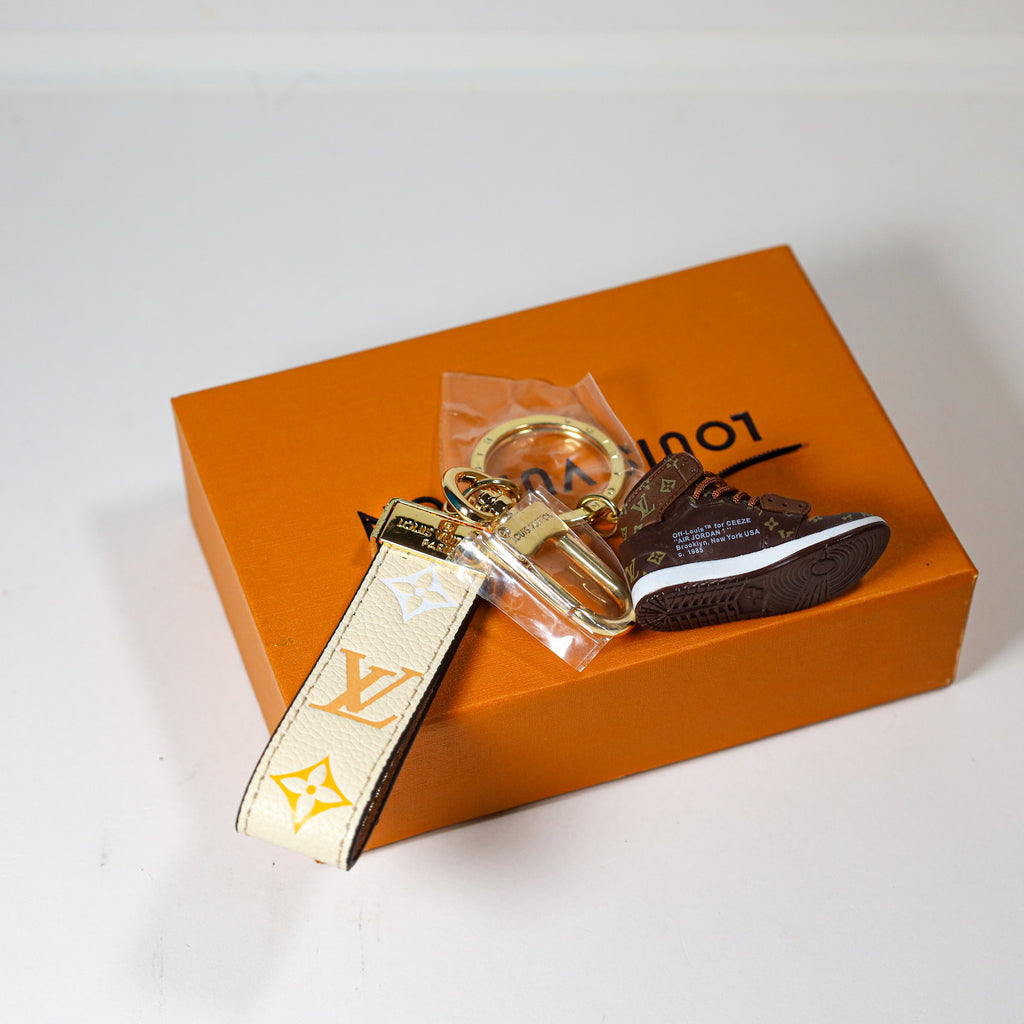 Side view of sneaker keychain with cream strap and round ring