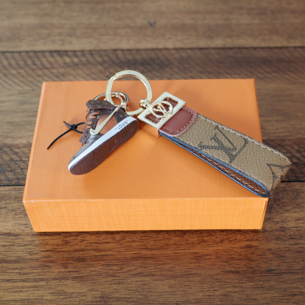 Sneaker keychain showing brown sole beside tan loop strap