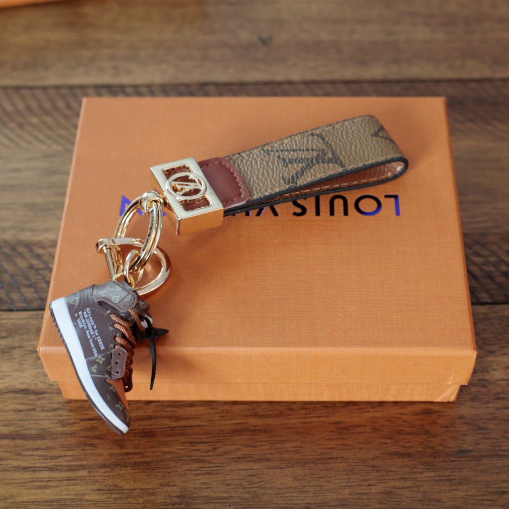 Tan monogram strap keychain with hanging sneaker charm