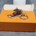 Brown miniature sneaker keychain with silver-tone ring on an orange box