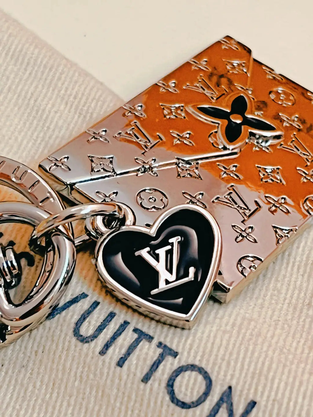 Black LV heart charm beside engraved envelope keychain