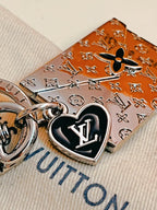 Black LV heart charm beside engraved envelope keychain