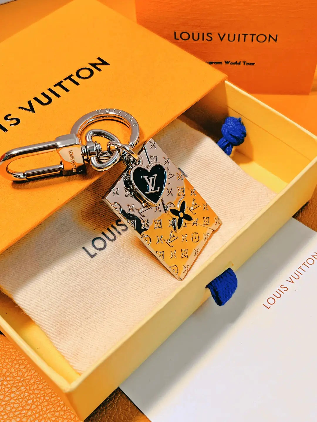 Black-accented envelope keychain displayed inside an orange box