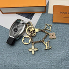 Gold-tone ornament keychain with LV and floral charms beside car key