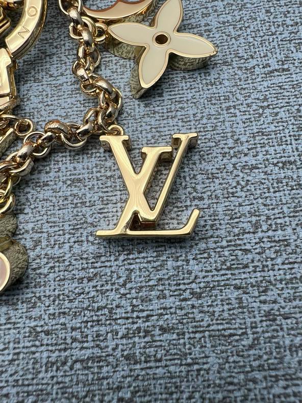 Gold-tone LV letter pendant and pale flower charm shown close up