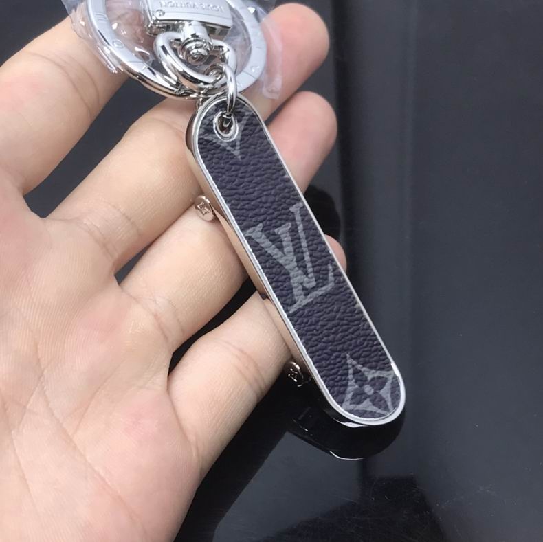Black monogram skateboard keychain held in an open palm